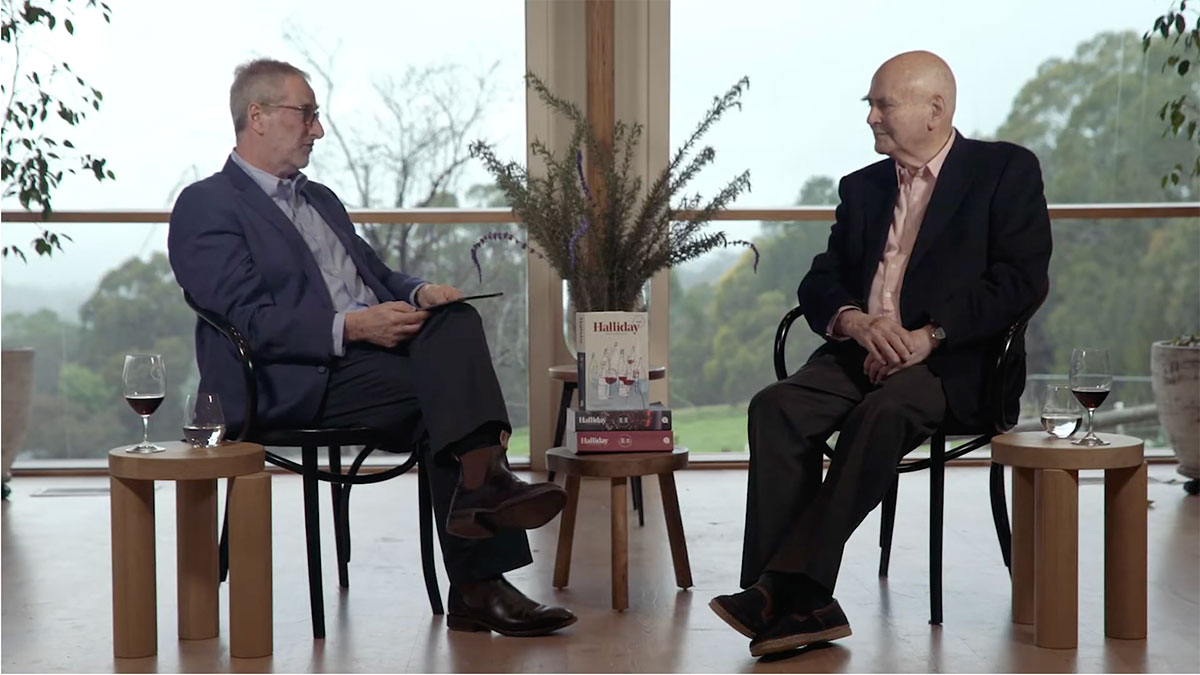 A still from the Halliday Awards live stream. It shows an MC speaking to James Halliday. They are both seated and have a glass of wine next to them.