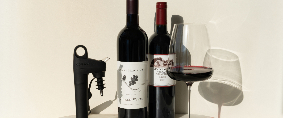 Two bottles of wine and a glass.