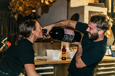 Someone pouring wine into another person's mouth with a magnum