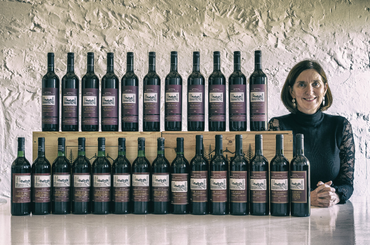 A woman stands with back vintages of a wine