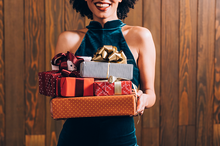 A person holding a stack of wrapped gifts