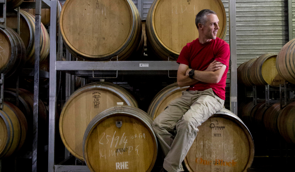 A man sits on a wine barrel