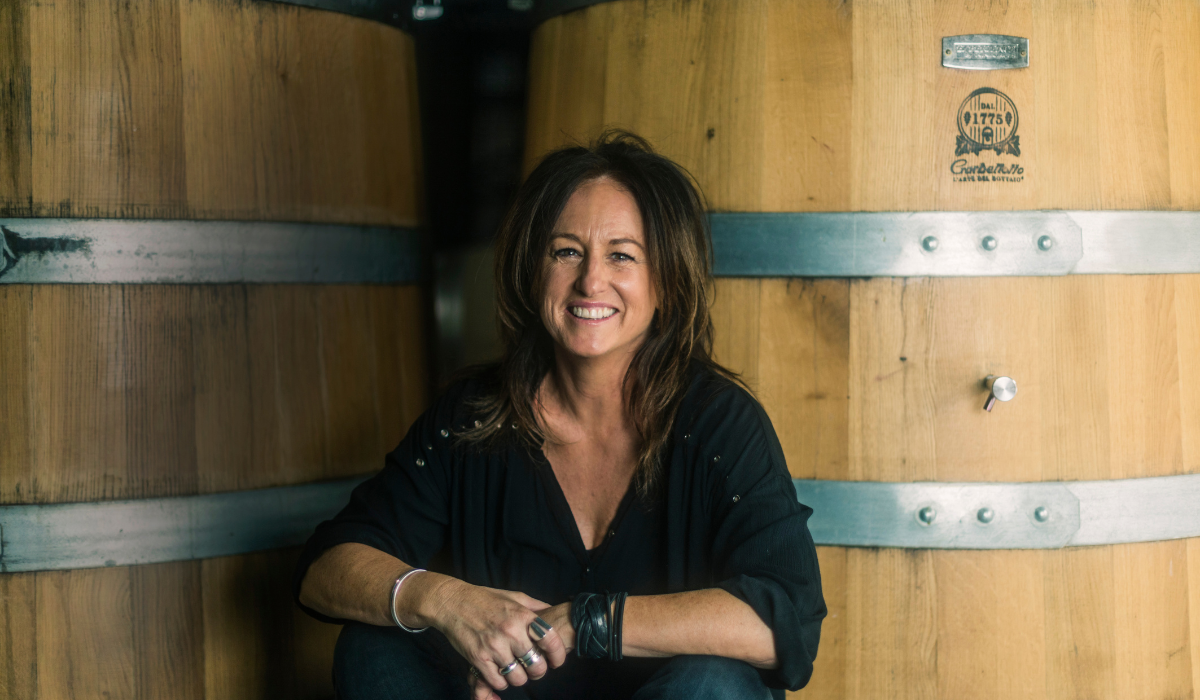 Winemaker sits in front of wine barrels