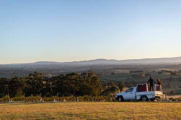 Bill Downie in the back of a ute with the Gippsland ranges in the background