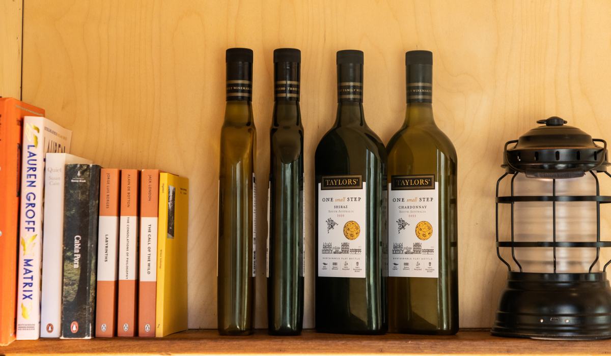 A bookshelf stacked with books and flat wine bottles