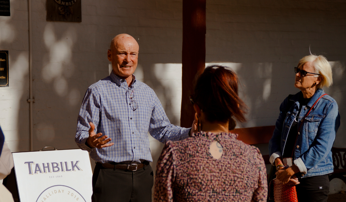 A man welcomes two women to his winery