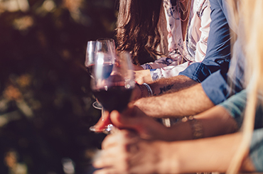 Friends leaning on balcony with glasses of red wine
