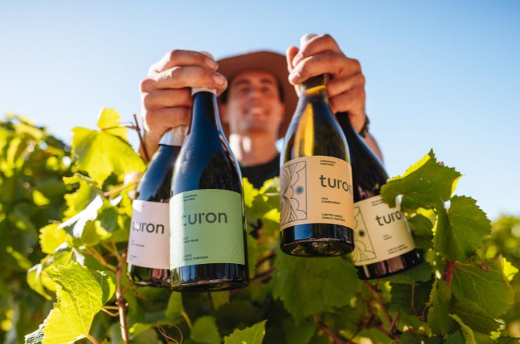 Turon White holding Turon Wine bottles among the grapevines