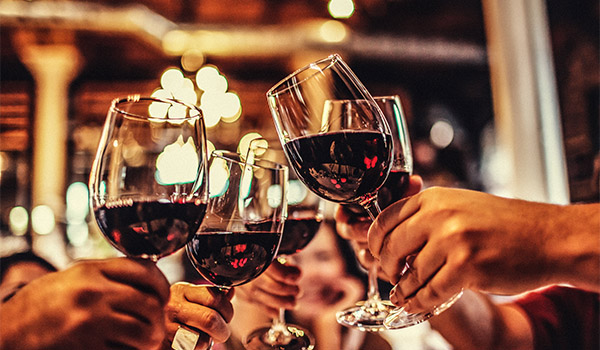 People clinking glasses filled with red wine