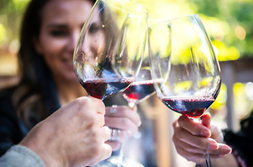 Three people toasting with glasses of red wine