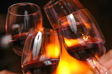 Four glasses of red wine with fire in the background
