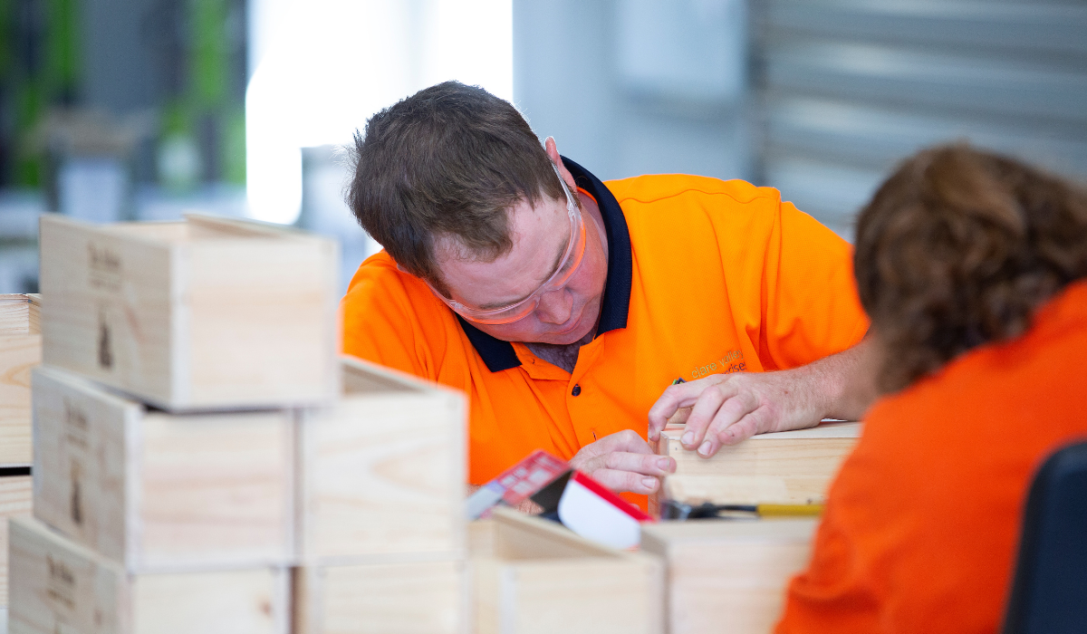 Two men in high-vis build wooden wine boxes