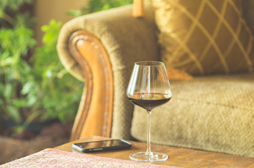 Glass of wine on coffee table in front of couch, next to smartphone