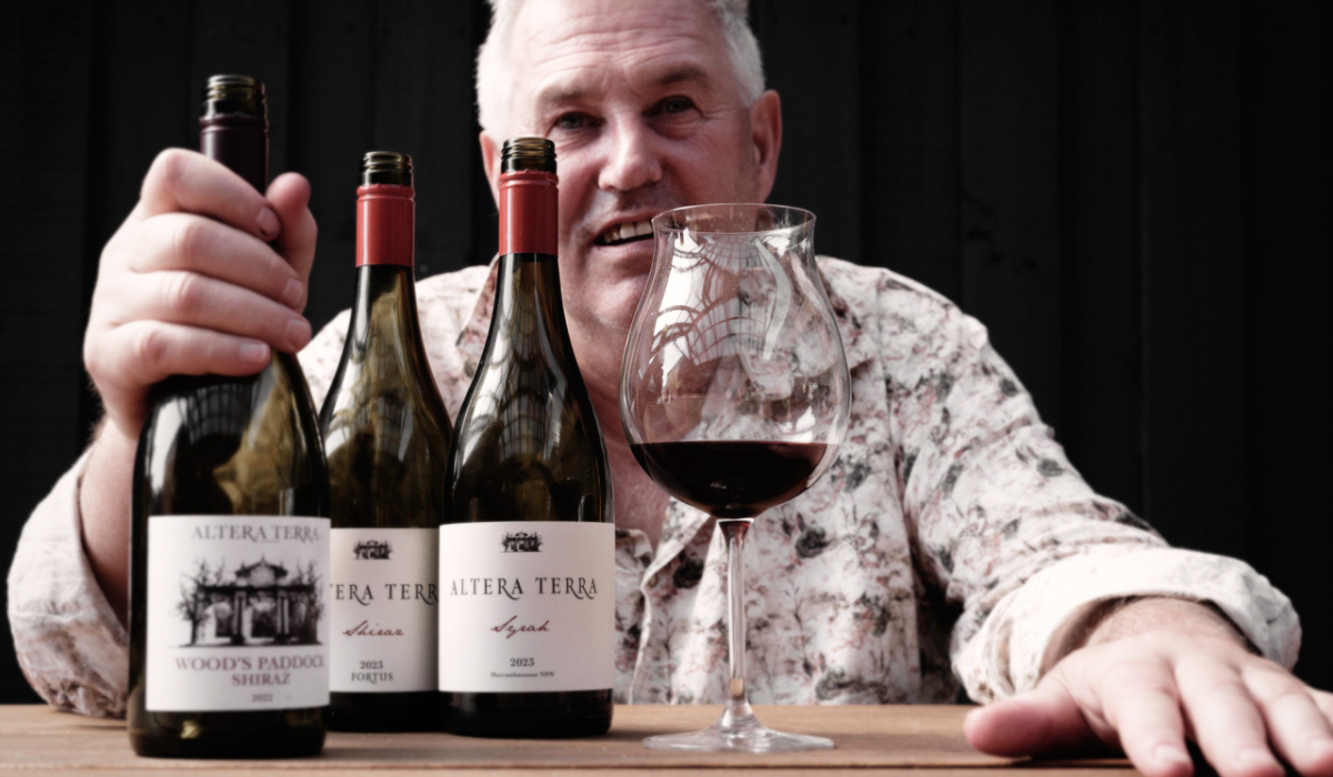 Winemaker Doug Neal sits behind three bottles and a full glass of red wine