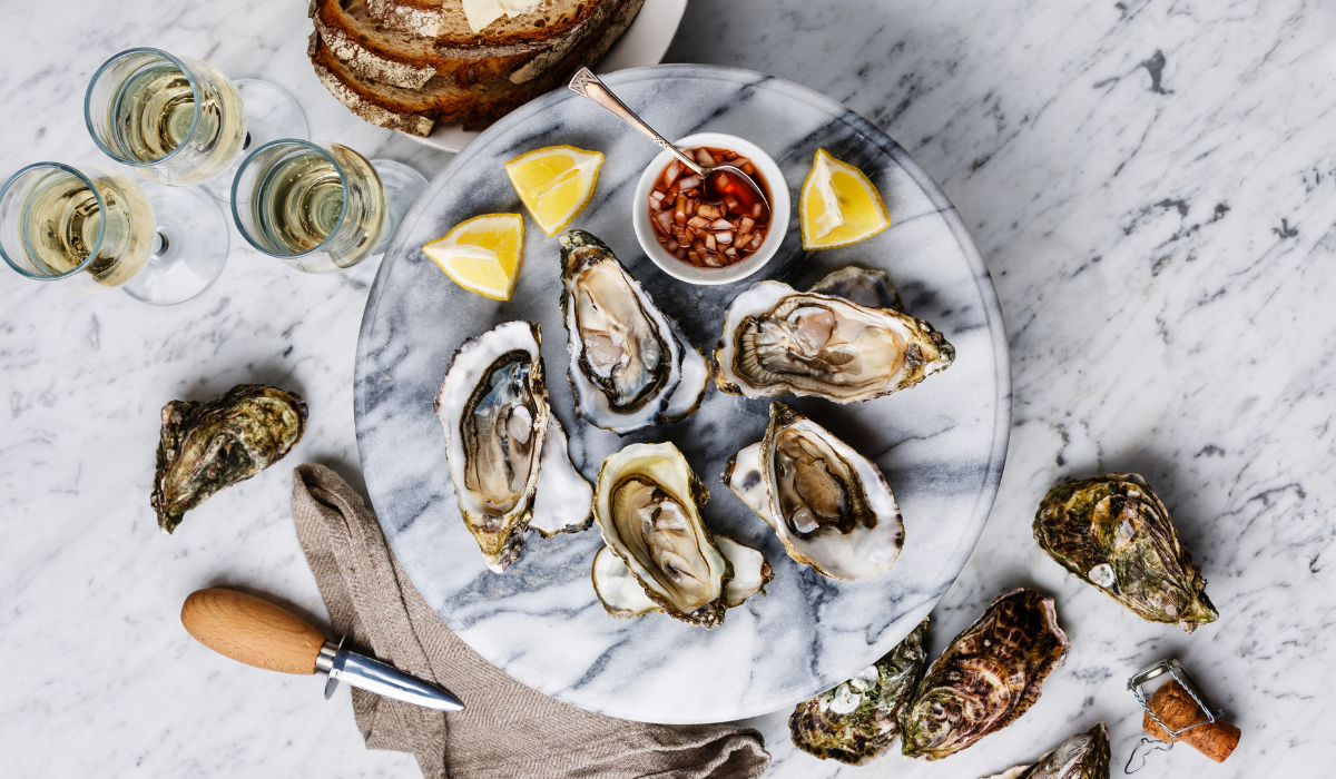 An overhead shot of a plate of freshly shucked oysters and wine