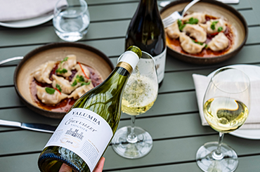 Yalumba viognier being poured into two glasses with the label facing up and dumplings in the background