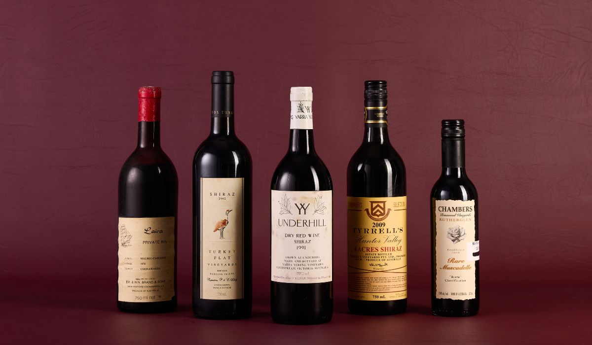 Bottles of wine in front of a maroon background