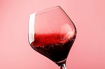 Glass of light red wine swirling against a pink background