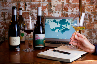 Two bottles of wine, two glasses of wine, a laptop and a notepad