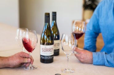 Several glasses and two bottles of light red wine. The wine glasses are being swirled.