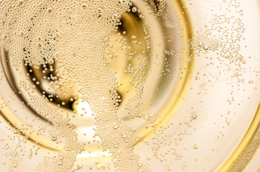 Close up of sparkling wine bubbles in a glass.