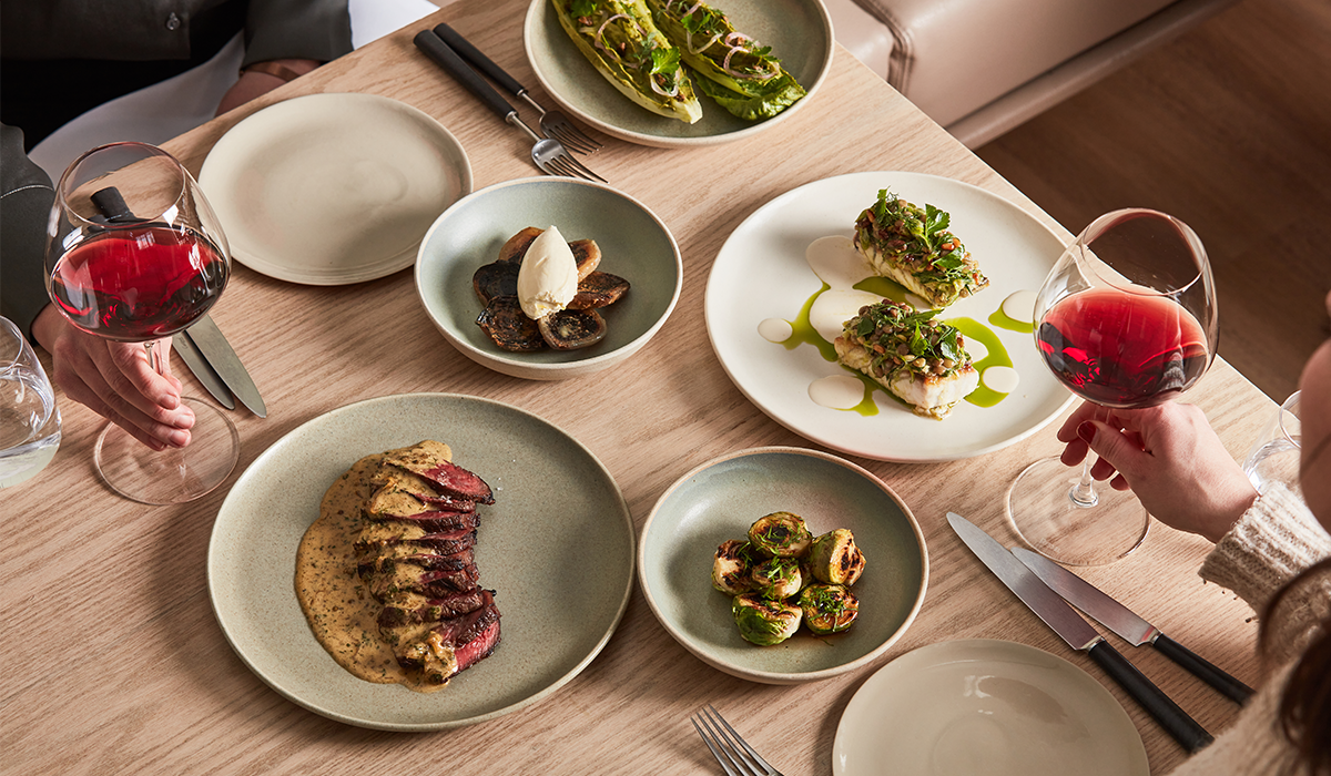 Bird's eye view of share plates and two glasses of red wine