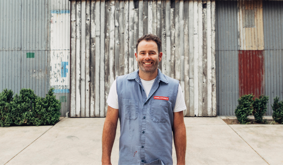 A male winemaker smiles in front of his winemaking shed