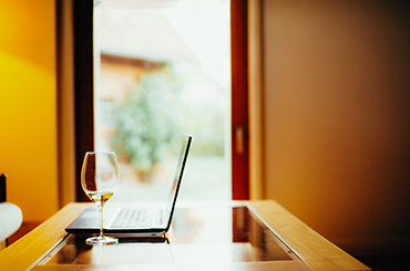 A laptop and wineglass set up for a tasting event at home