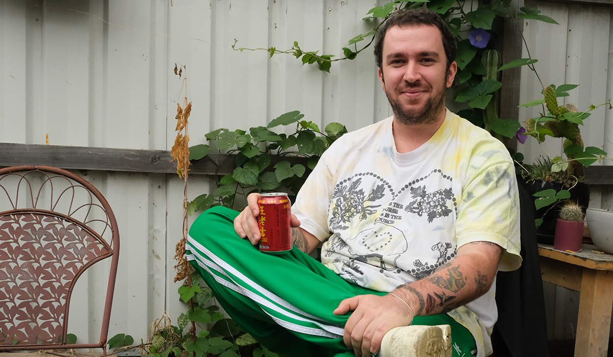 Jack Shaw sitting down with his knee crossed over his other leg, holding a can of beer