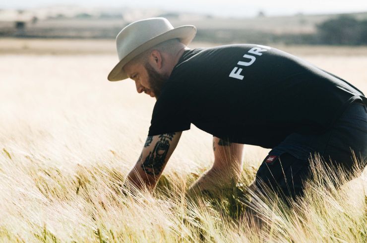 A man crouches down in a wheat field