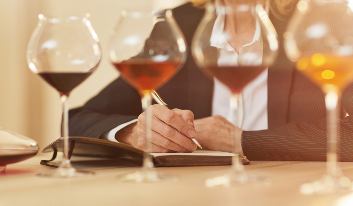 A line-up of wines and a woman making notes in the background