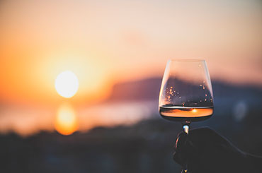 Man holding glass of rosé wine with sea in the background