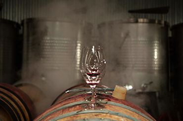 Red wine in glass sitting on barrels