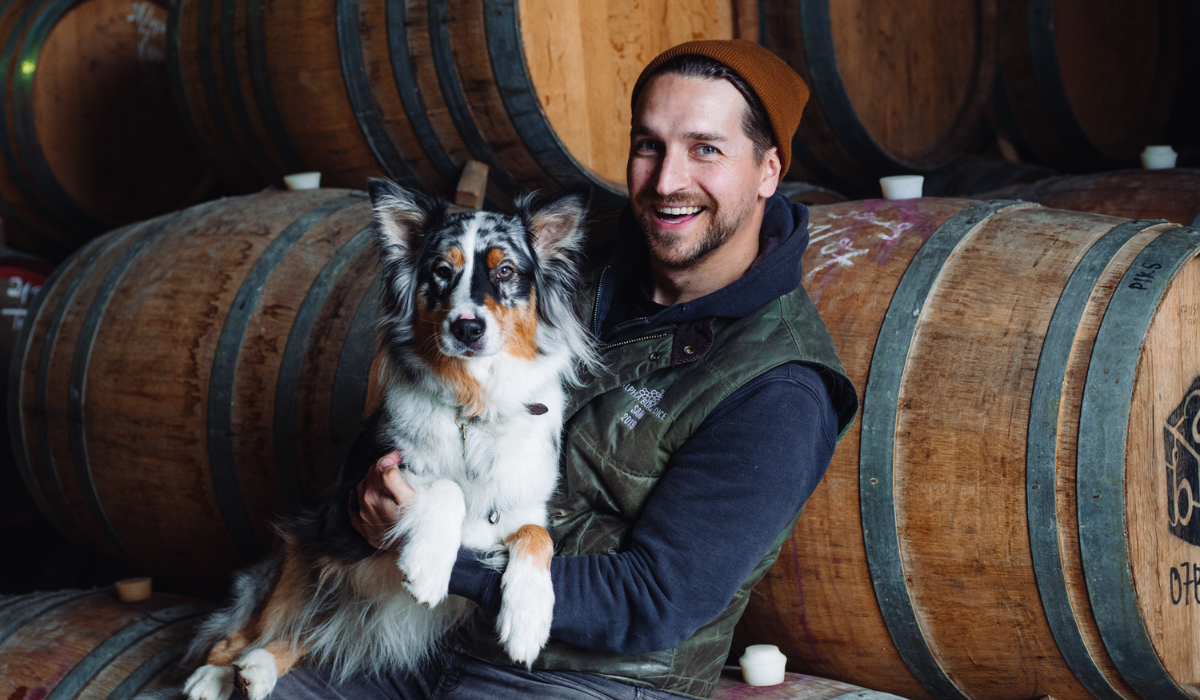 Winemaker Sam Berketa and his dog in front of a wine barrel