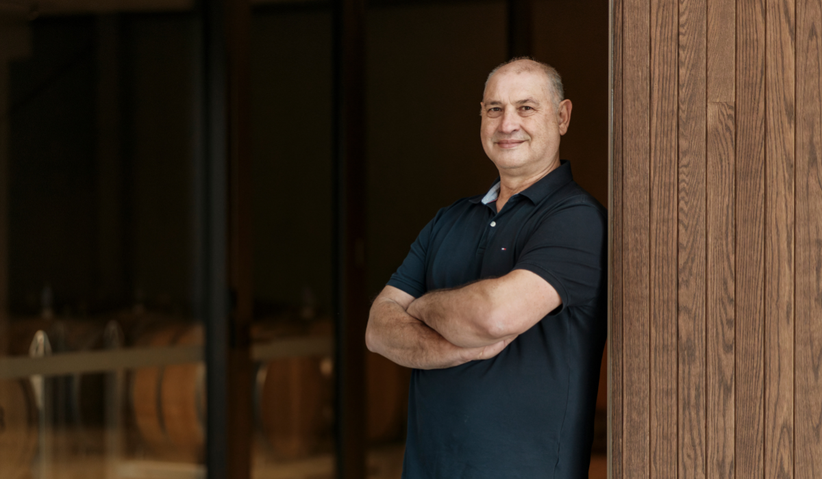 A man poses with his arms crossed leaning on a wall