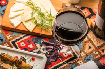 Glass of Georgian red wine alongside platters of food
