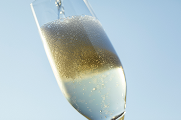 Close up of bubbles in a sparkling glass, wine glass is on an angle.