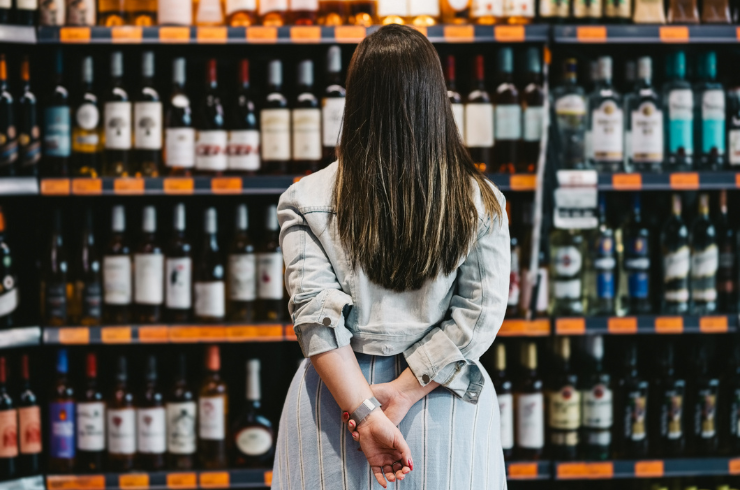 A woman chooses wine from a shelf