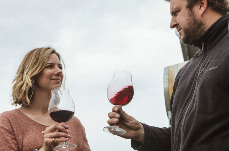 A man and a woman holding glasses of red wine