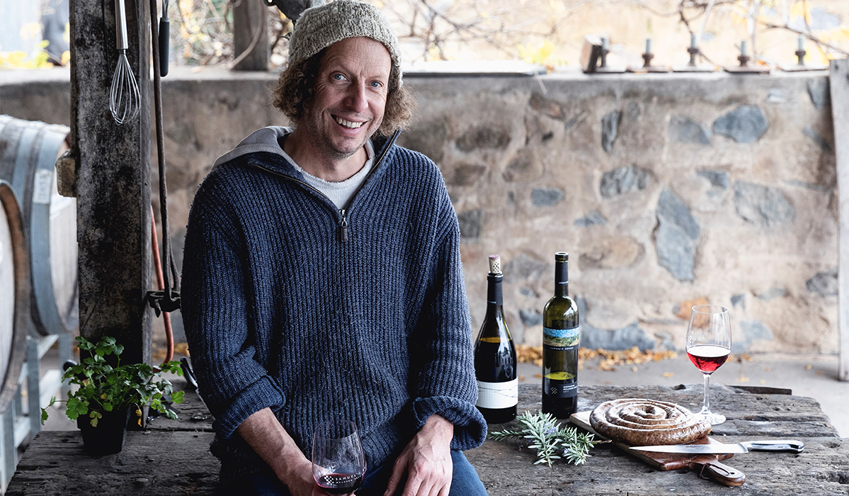 Justin sitting on a table with food and wine in the background