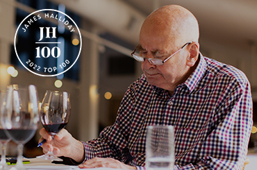 James Halliday sitting getting ready to taste a red wine, he has glasses of red wines in front of him