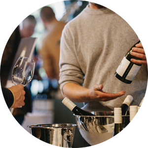 A man serving wine to a guest at a Halliday event.