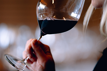 Woman sipping red wine from a Riedel glass