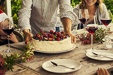 Pavlova and glasses of red wine on wooden outdoor table