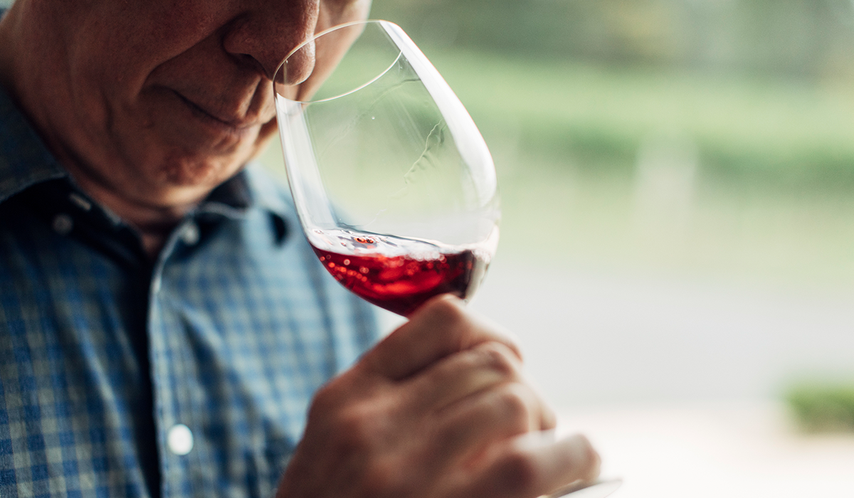 A man smelling a glass of red wine