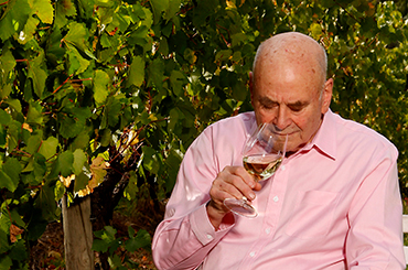 James Halliday in the vineyard sniffing a glass of white wine